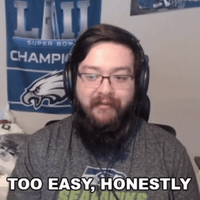 A Man With A Beard And Headphones Is Sitting In Front Of A Super Bowl Banner . GIF