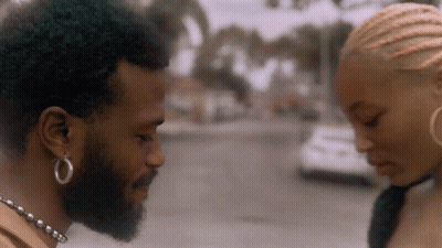 A Man With A Beard And Hoop Earrings Is Looking At A Woman GIF