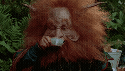 A Man With A Beard And Horns Is Holding A Bottle In Front Of His Face GIF