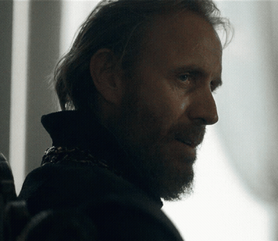 A Man With A Beard And Long Hair Is Looking At Something GIF