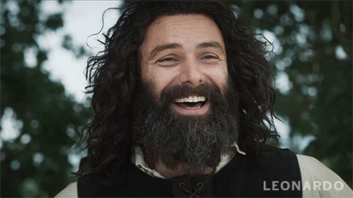 A Man With A Beard And Long Hair Is Smiling And The Name Leonardo Is Visible In The Corner GIF
