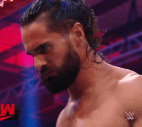 A Man With A Beard And Long Hair Is Standing In Front Of A W Logo GIF