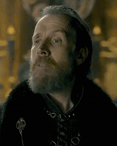 A Man With A Beard And Long Hair Is Wearing A Fur Coat . GIF