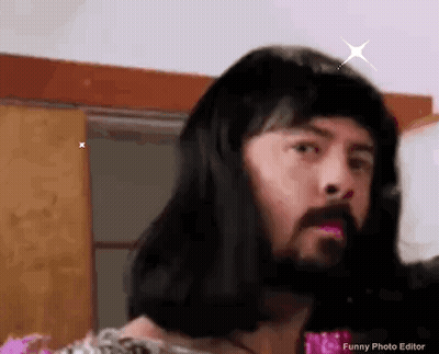 A Man With A Beard And Long Hair Is Wearing A Wig And Making A Funny Face . GIF