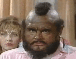 A Man With A Beard And Mohawk Is Looking At The Camera . GIF