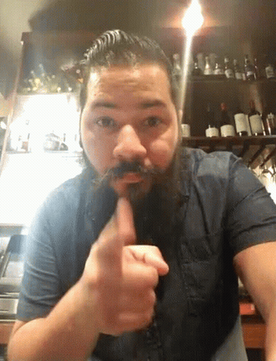 A Man With A Beard And Mustache Holds His Finger To His Mouth GIF