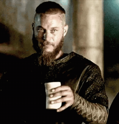 A Man With A Beard And Mustache Is Holding A Cup Of Coffee . GIF