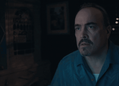 A Man With A Beard And Mustache Is Looking At Something In The Dark GIF