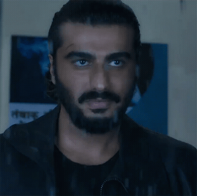 A Man With A Beard And Mustache Is Looking At The Camera In Front Of A Sign That Says ' A ' On It GIF