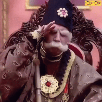A Man With A Beard And Mustache Is Sitting In A Chair With His Hand On His Face . GIF