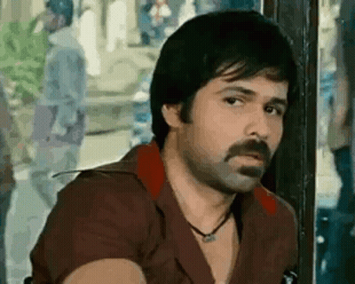 A Man With A Beard And Mustache Is Sitting In Front Of A Window . GIF