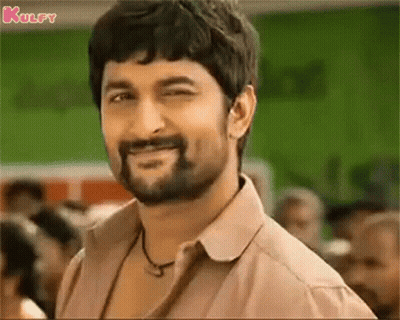 A Man With A Beard And Mustache Is Smiling And Looking At The Camera . GIF