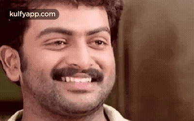A Man With A Beard And Mustache Is Smiling And Looking At The Camera . GIF