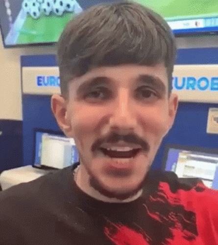 A Man With A Beard And Mustache Is Smiling And Looking At The Camera . GIF