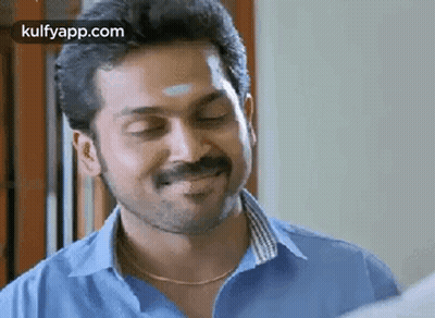 A Man With A Beard And Mustache Is Smiling With His Eyes Closed And Wearing A Blue Shirt . GIF