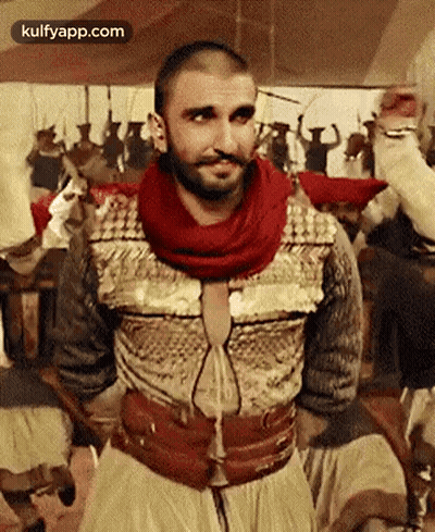 A Man With A Beard And Mustache Is Standing In Front Of A Crowd Of People . GIF