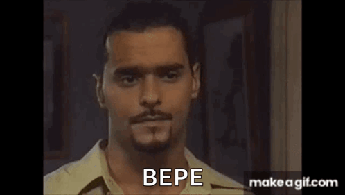 A Man With A Beard And Mustache Is Standing In Front Of A Door And Talking To Someone . GIF