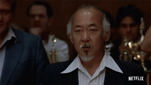 A Man With A Beard And Mustache Is Standing In Front Of A Group Of People . GIF