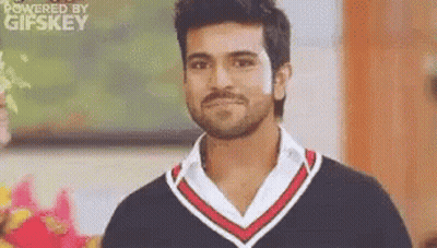 A Man With A Beard And Mustache Is Wearing A Black And Red Sweater And A White Shirt . GIF