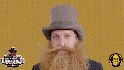 A Man With A Beard And Mustache Is Wearing A Top Hat Sponsored By The 2017 World Beard & Moustache Championship GIF
