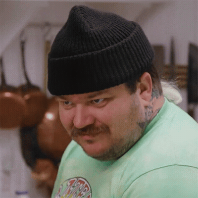 A Man With A Beard And Mustache Wearing A Green Shirt And A Black Hat GIF