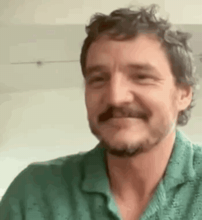 A Man With A Beard And Mustache Wearing A Green Shirt Is Smiling . GIF