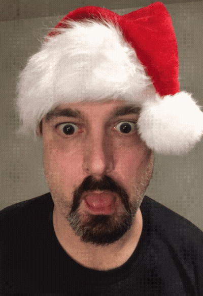 A Man With A Beard And Mustache Wearing A Santa Hat GIF