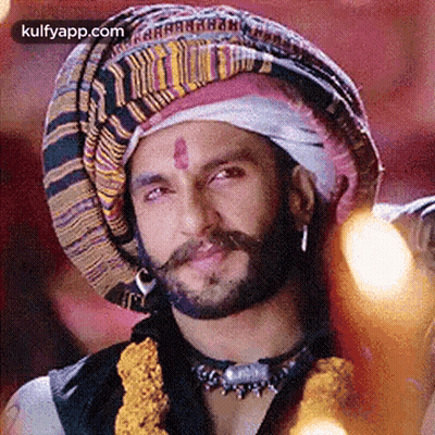A Man With A Beard And Mustache Wearing A Turban And A Necklace . GIF