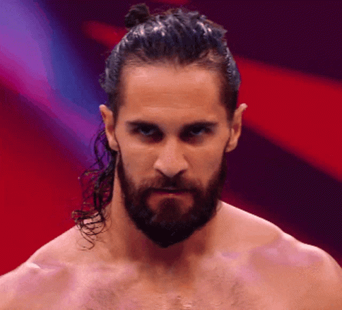 A Man With A Beard And Ponytail Looks At The Camera GIF