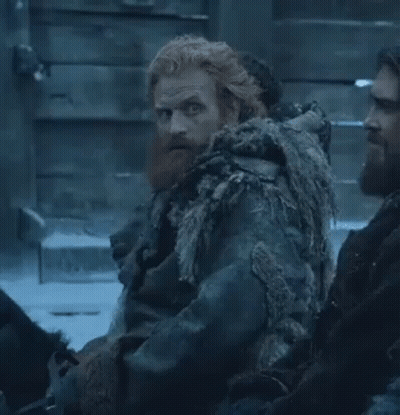 A Man With A Beard And Red Hair Is Sitting Next To Another Man In A Snowy Room . GIF
