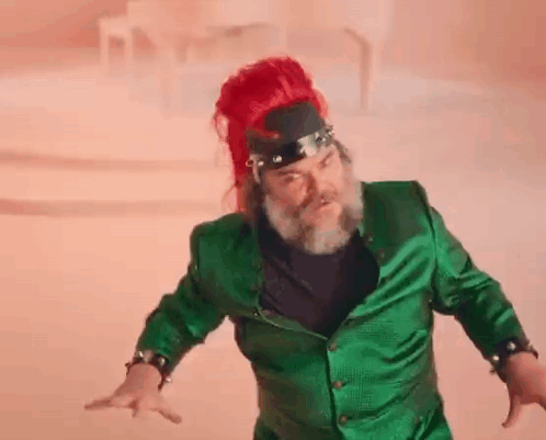 A Man With A Beard And Red Hair Is Wearing A Green Jacket And A Red Headband . GIF