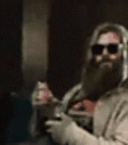 A Man With A Beard And Sunglasses Is Holding A Cup Of Coffee And A Spoon . GIF