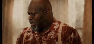 A Man With A Beard And Suspenders Is Standing In Front Of A Window In A Room . GIF