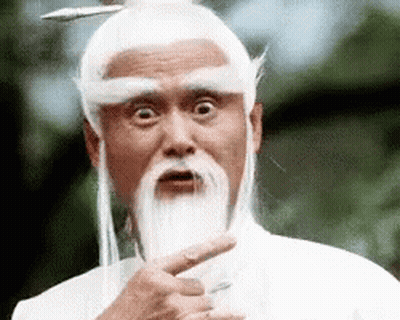 A Man With A Beard And White Hair Is Pointing At The Camera . GIF