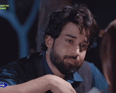 A Man With A Beard Giving A Peace Sign In Front Of A Sign That Says Urshid Fans GIF