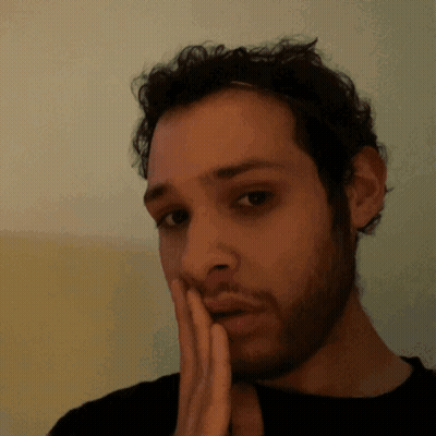 A Man With A Beard Has His Hand On His Chin GIF