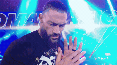 A Man With A Beard Holds His Hands Together In Front Of A Sign That Says Dynamite GIF
