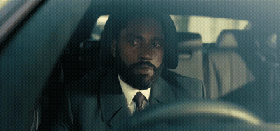 A Man With A Beard In A Suit And Tie Is Driving A Car GIF
