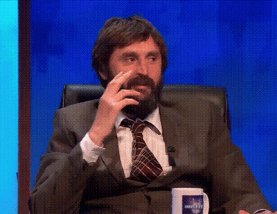 A Man With A Beard In A Suit And Tie Is Sitting In A Chair Talking On A Television Show . GIF