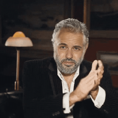 A Man With A Beard In A Suit Is Clapping His Hands . GIF