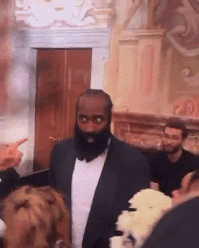 A Man With A Beard In A Suit Stands In Front Of A Group Of People GIF