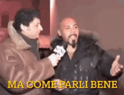 A Man With A Beard Is Being Interviewed By Another Man While Holding A Microphone . GIF