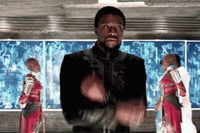A Man With A Beard Is Clapping His Hands In Front Of A Group Of People In Armor . GIF