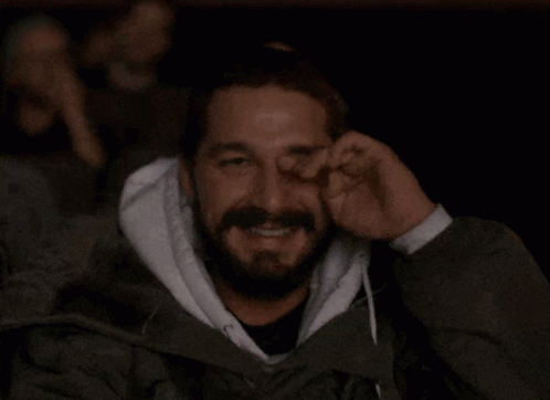 A Man With A Beard Is Covering His Face With His Hand GIF