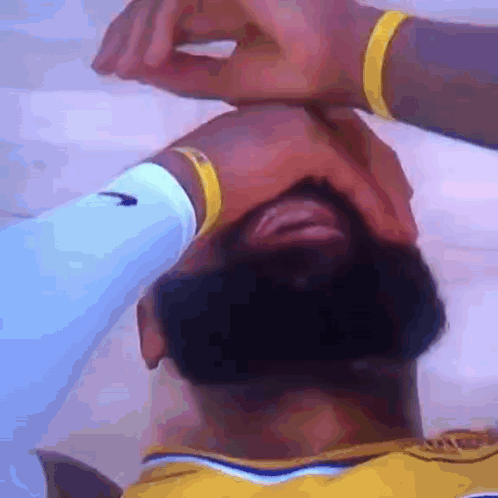 A Man With A Beard Is Covering His Face With His Hands . GIF