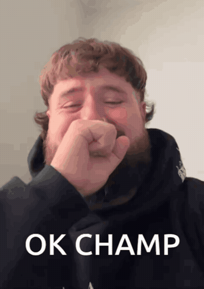 A Man With A Beard Is Covering His Mouth With His Fist And The Words Ok Champ Are On The Bottom GIF