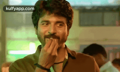 A Man With A Beard Is Covering His Mouth With His Hands . GIF