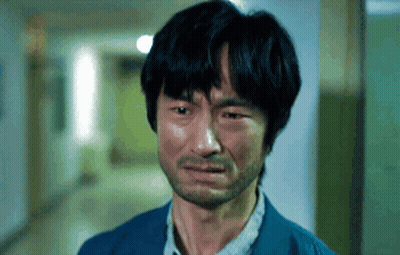 A Man With A Beard Is Crying In A Hallway With His Eyes Closed GIF