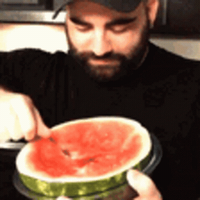 A Man With A Beard Is Cutting A Slice Of Watermelon GIF