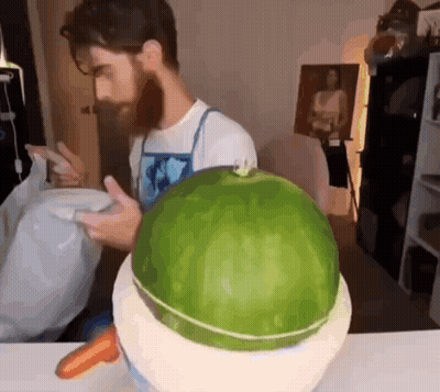 A Man With A Beard Is Cutting A Watermelon In Half GIF